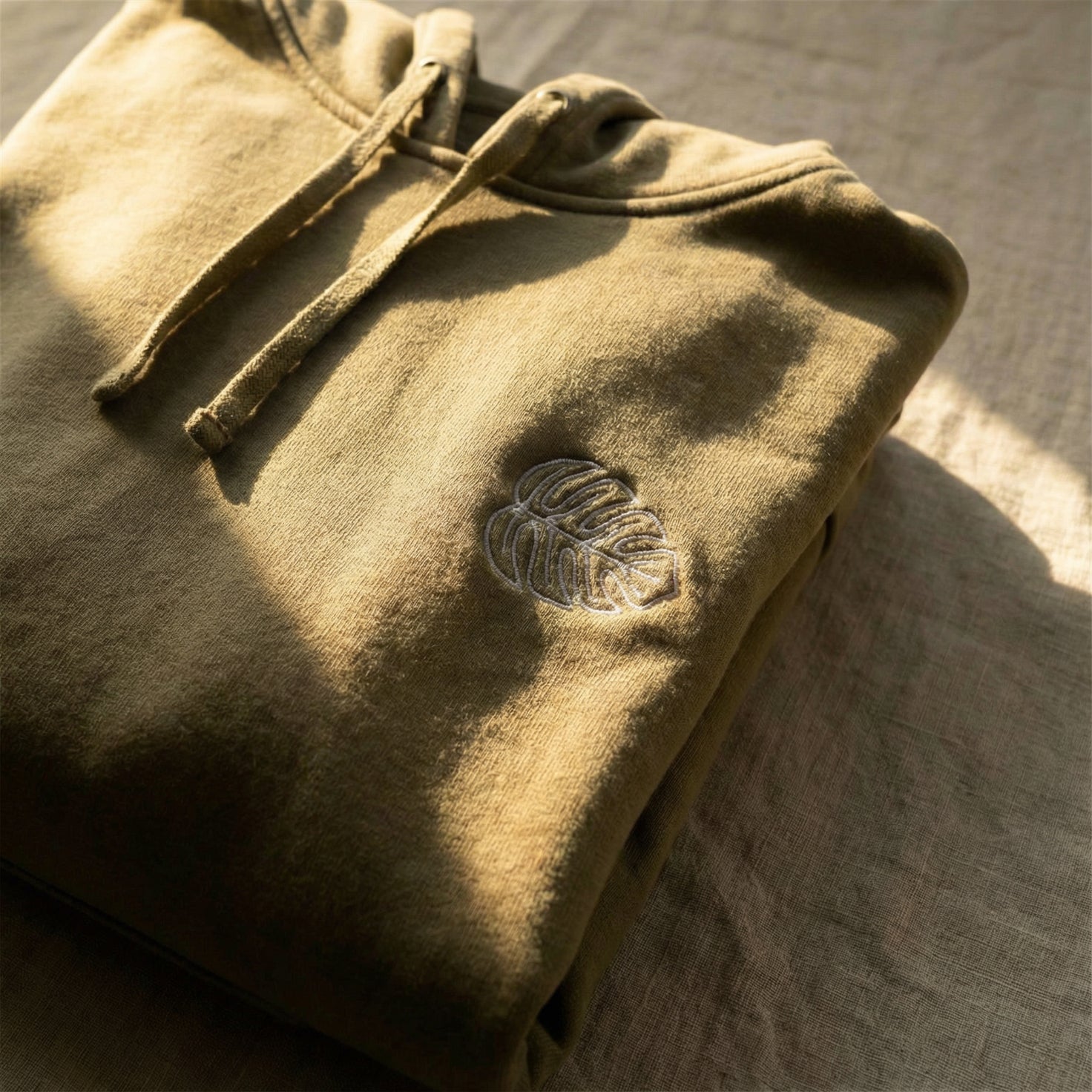 Folded beige fabric with a leaf emblem on a textured surface